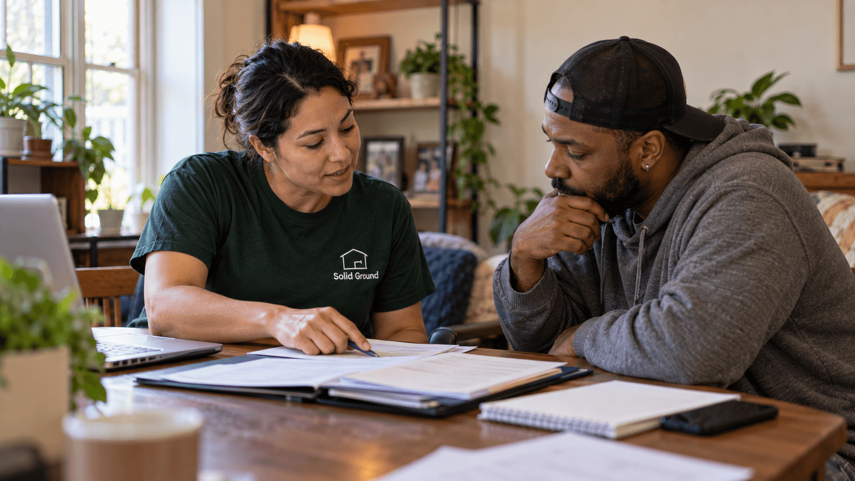 A Solid Ground navigator reviewing paperwork with a neighbor at their home table